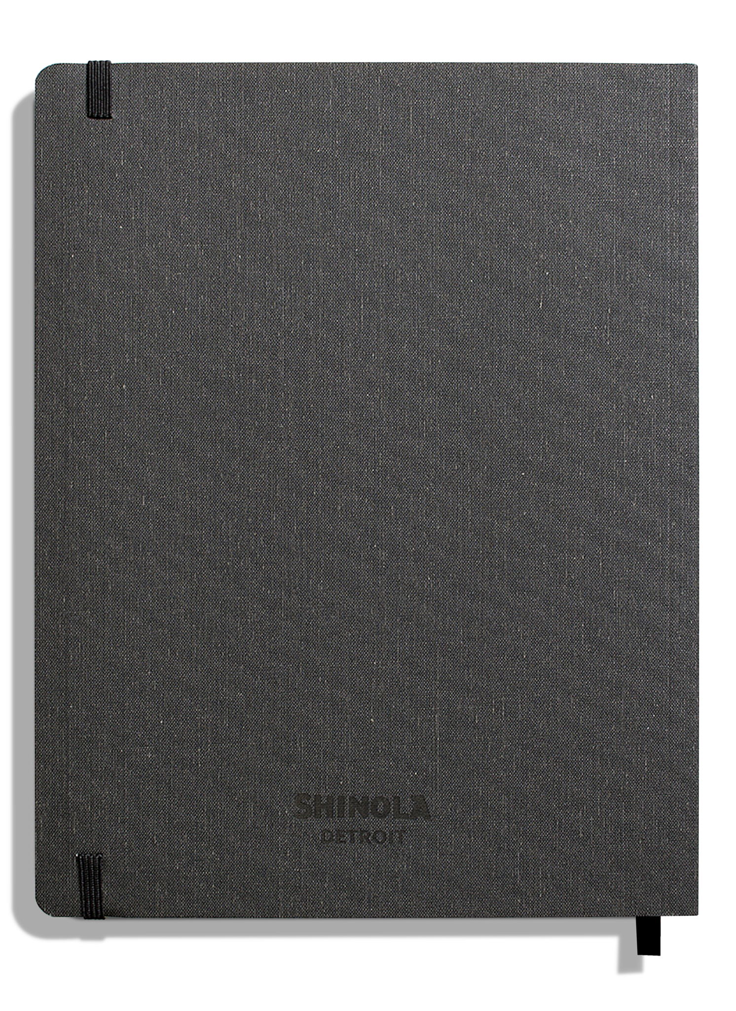 A closed, charcoal linen-bound Large Soft Ruled Journal by Shinola, with smyth-sewn binding and black elastic closures on the top left and bottom right corners.