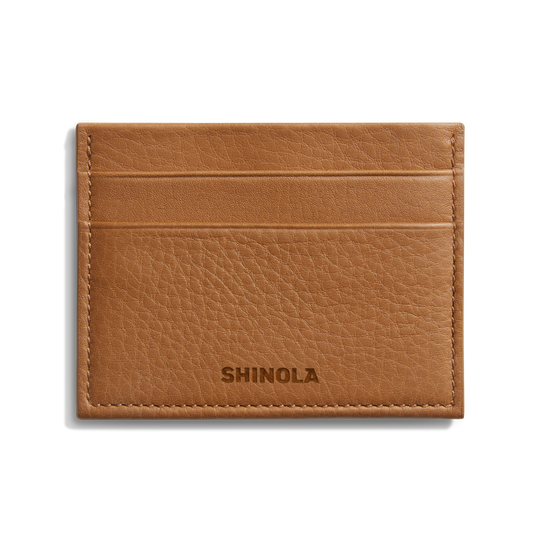 The Shinola 5 Pocket Card Holder - Tan is a compact leather wallet with five slots, visible edge stitching, and the Shinola name embossed on the front, blending style and function in a slim design.