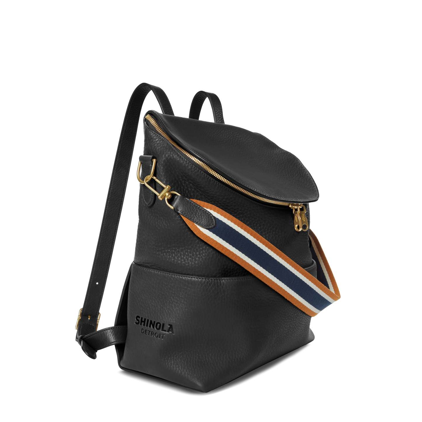 The Shinola Convertible Pocket Backpack - Brand Stripe / Black features gold hardware, a zippered top, and an adjustable navy, white, and brown striped strap. The front displays the Shinola Detroit logo—ideal for hands-free style.