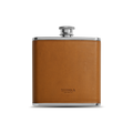 The Leather Wrapped Flask - Tan by Shinola features a stainless steel body with a tan Italian Vachetta leather wrap and screw cap, the Shinola name embossed on the front, displayed against a plain white background.