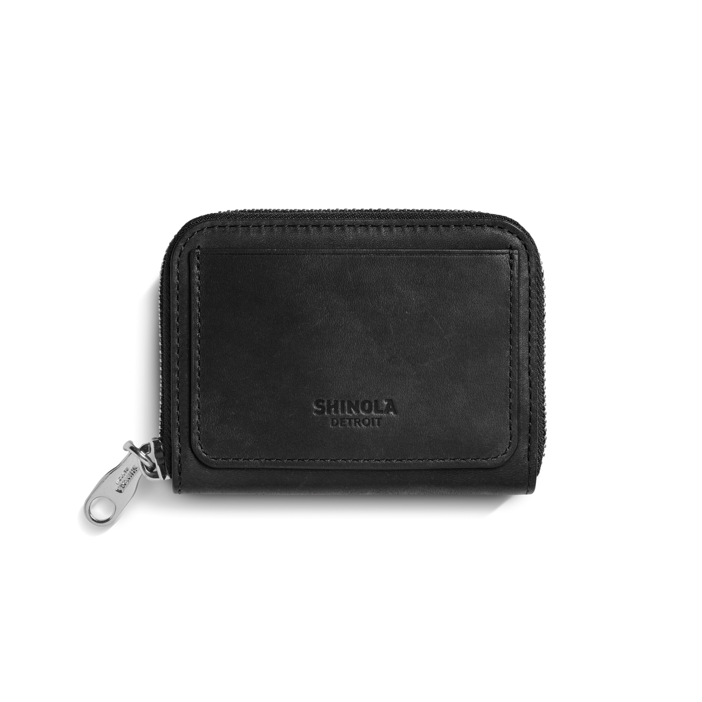 The Shinola Pocket Small Zip Around Wallet in black natural leather features a minimalist design, embossed "Shinola Detroit" on the front, and a silver zipper pull. It is photographed against a plain white background.