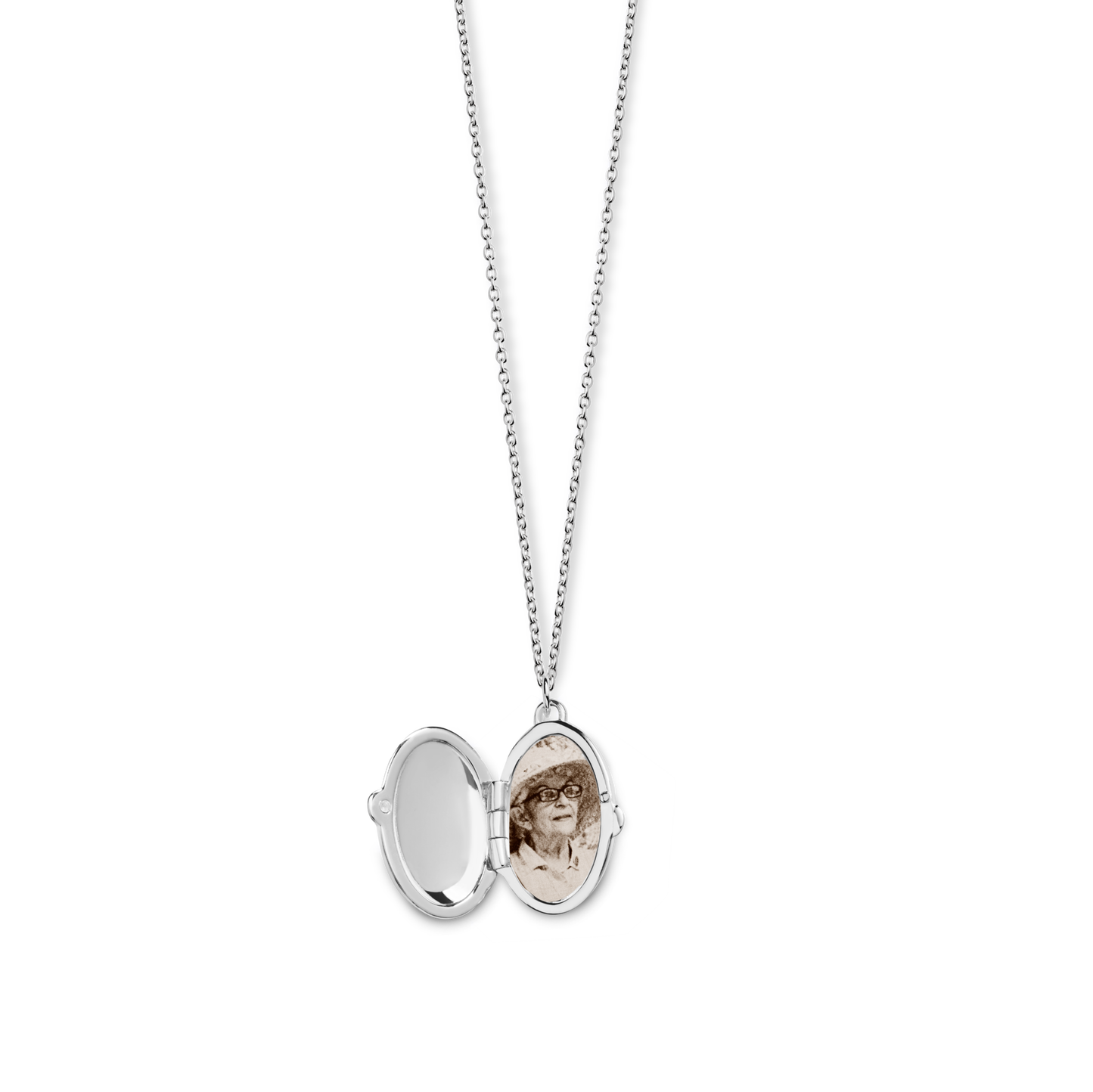The Shinola Heirloom Statement Locket Necklace in sterling silver hangs open, showing a mirror on one side and a sepia photo of a person with glasses and a hat on the other, set against a plain white background.
