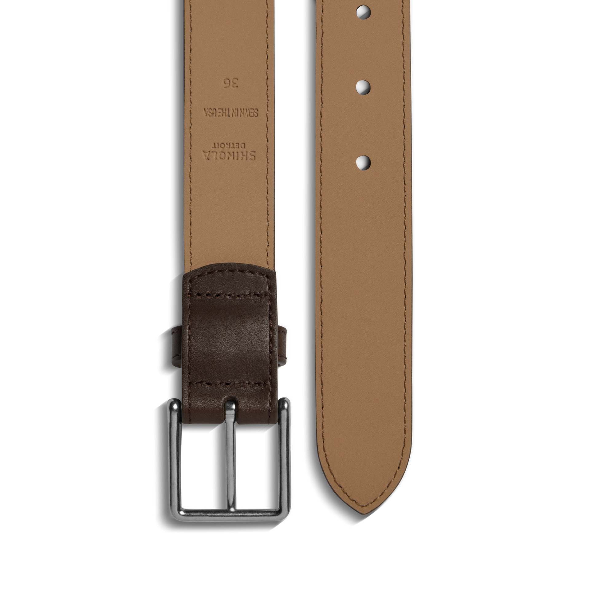 The 1 1/4" Dress Belt by Shinola is crafted from natural leather with a silver buckle. Shown flat on white, the brown belt features a tan inner side with size and brand details stamped near the buckle.