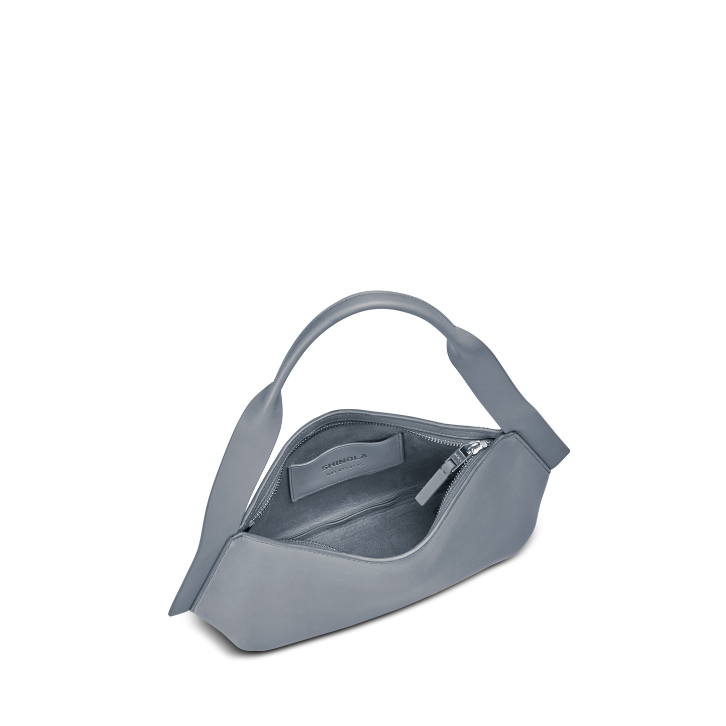 The Small Derby Shoulder Bag - Mist by Shinola is a modern gray petite bag with a curved top handle, featuring a minimalist natural leather interior and designer label, shown partially unzipped on a plain white background.