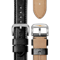 Close-up of the Shinola 24mm Black Leather Watch Strap (24\22), showing both black front and tan stitched back sides. The silver buckle features a small orange logo.