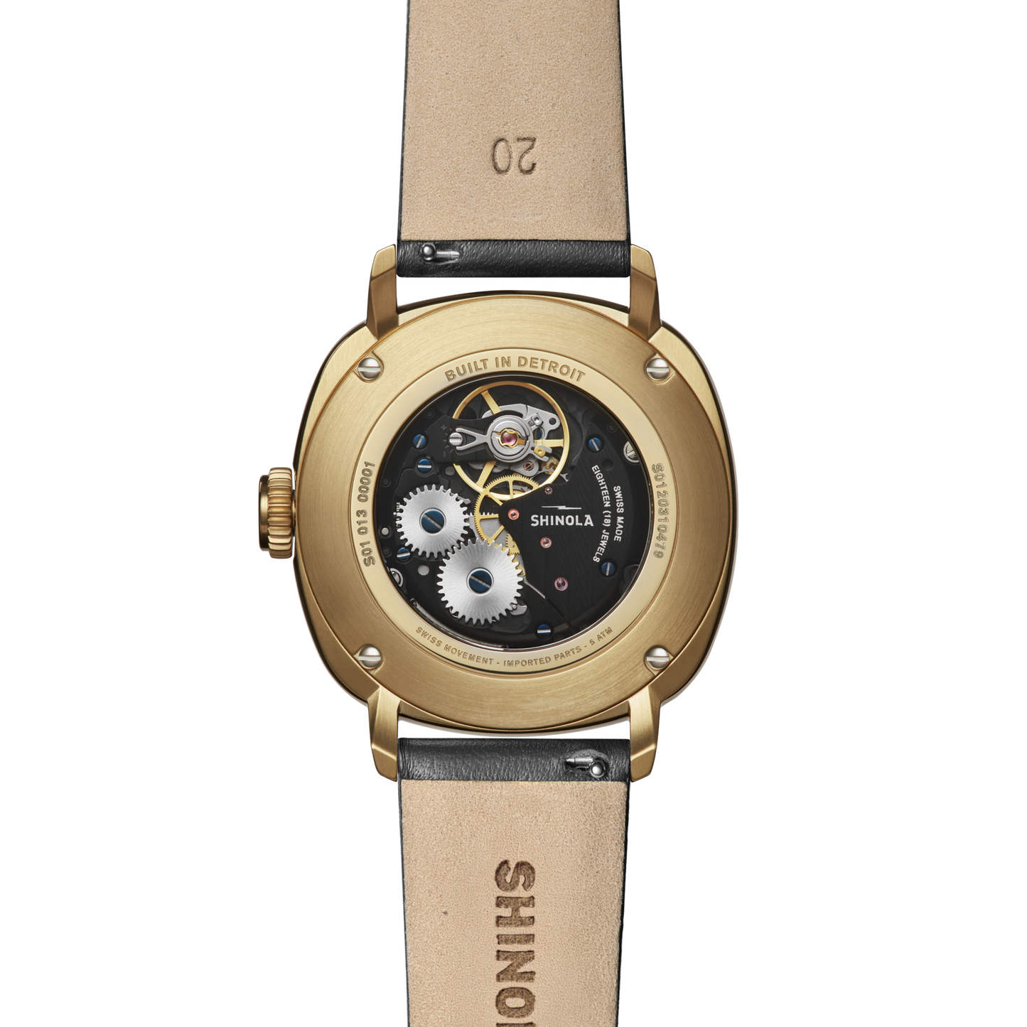 Close-up of the back of the Shinola Mechanic Watch - Black/Gold, showcasing its gold case, exhibition case back revealing intricate gears, and brown leather strap stamped with SHINOLA and the number 20.