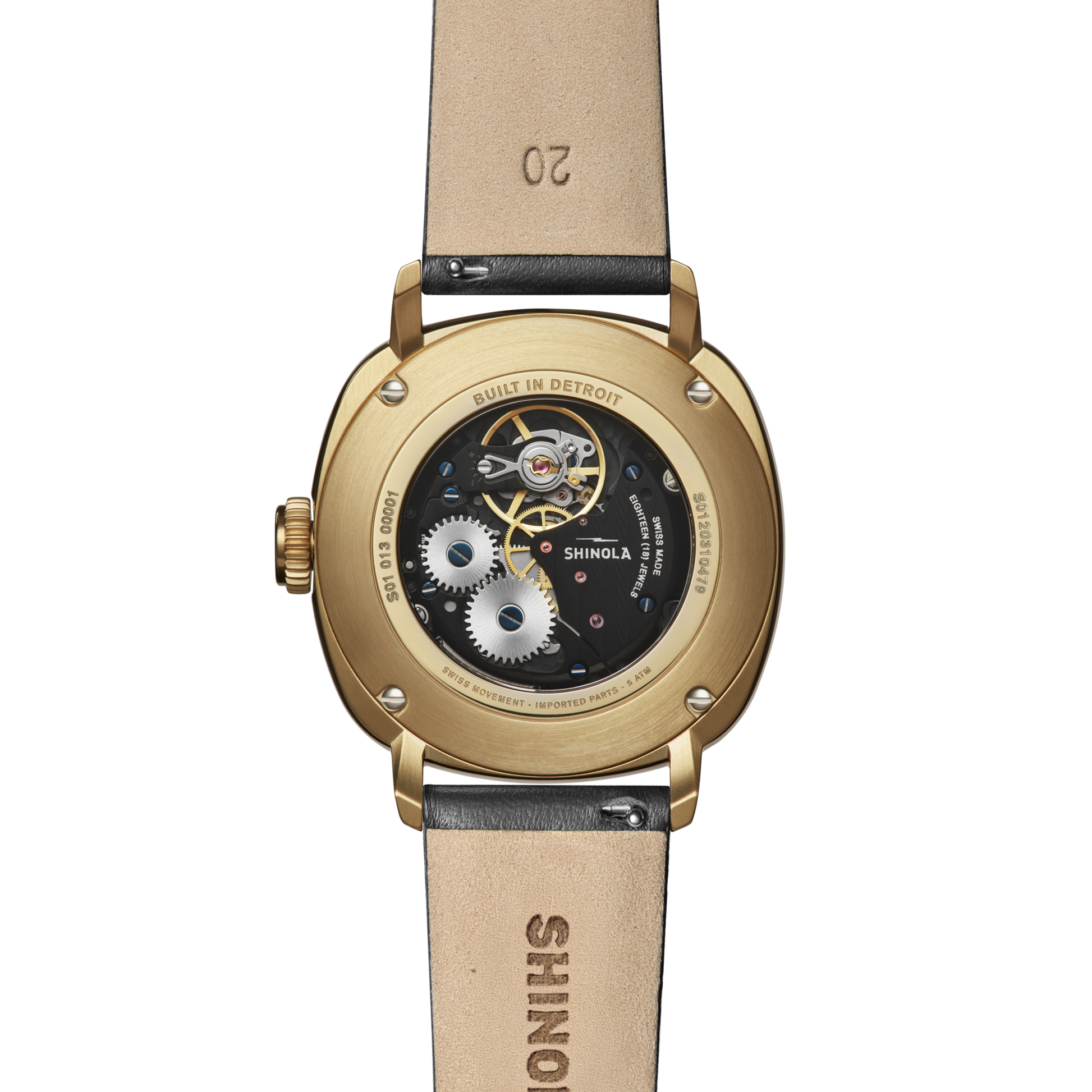 Close-up of the back of the Shinola Mechanic Watch - Black/Gold, showcasing its gold case, exhibition case back revealing intricate gears, and brown leather strap stamped with SHINOLA and the number 20.