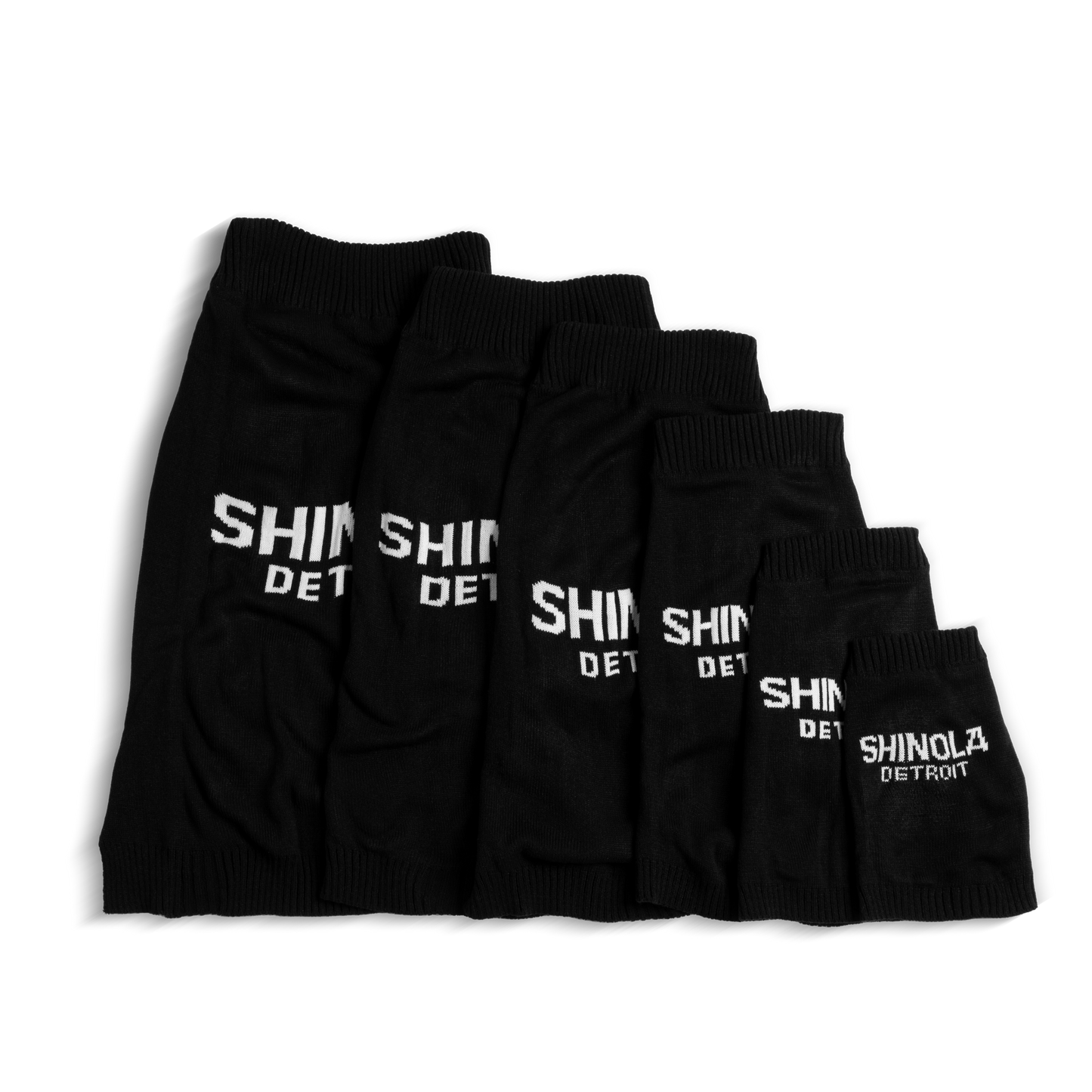 Six Shinola Dog Sweater - Black knit sleeves in various sizes, each embroidered with SHINOLA DETROIT, are arranged side by side on a white background, resembling a chic collection of canine pullovers.