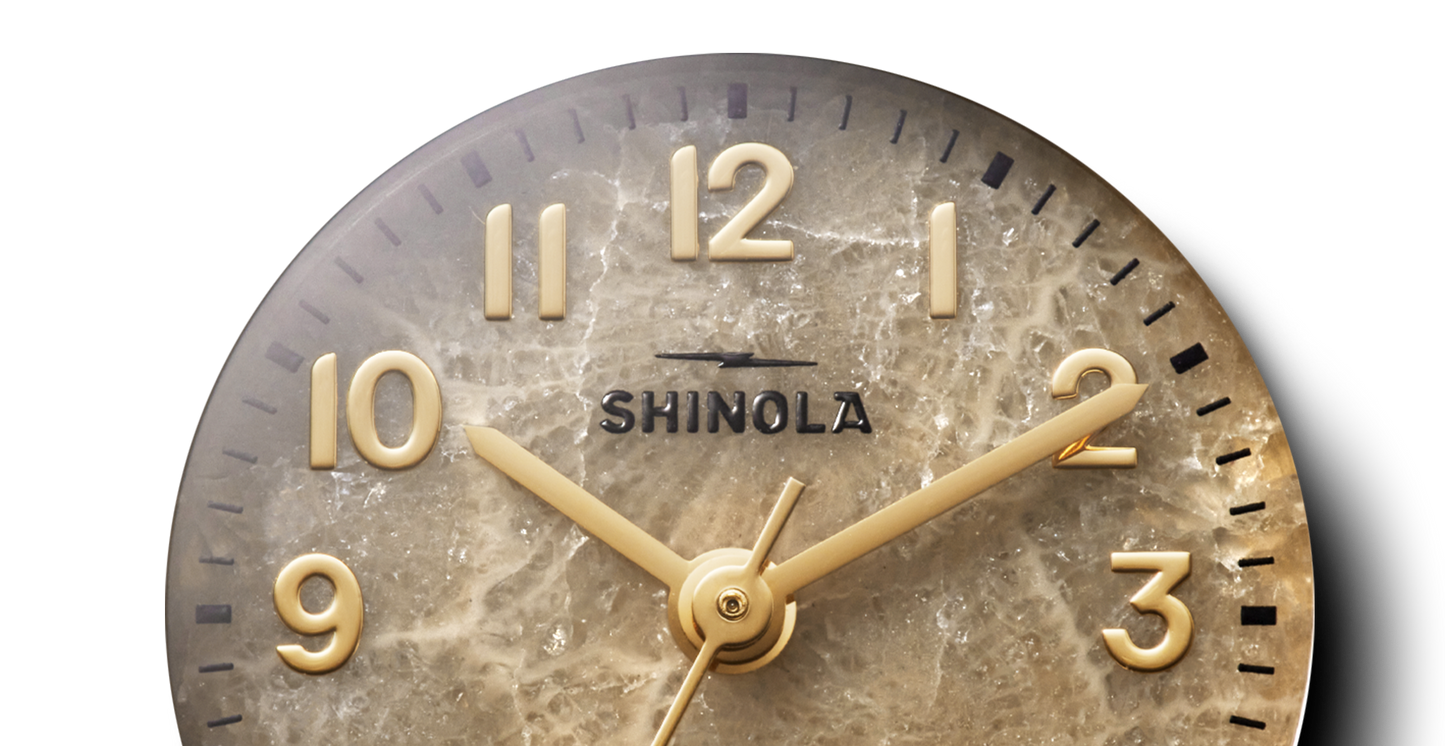 Close-up of the Shinola Runabout Watch – Petoskey, featuring gold numerals and hands on a marbled Petoskey stone dial. The Detroit-assembled timepiece shows approximately 2:09.