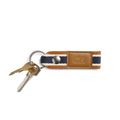 Two keys on a silver keyring are attached to the Shinola Webbing Keychain - Brand Stripe / Tan, featuring dark blue, white, and brown stripes and a tan leather patch perfect for monogramming.