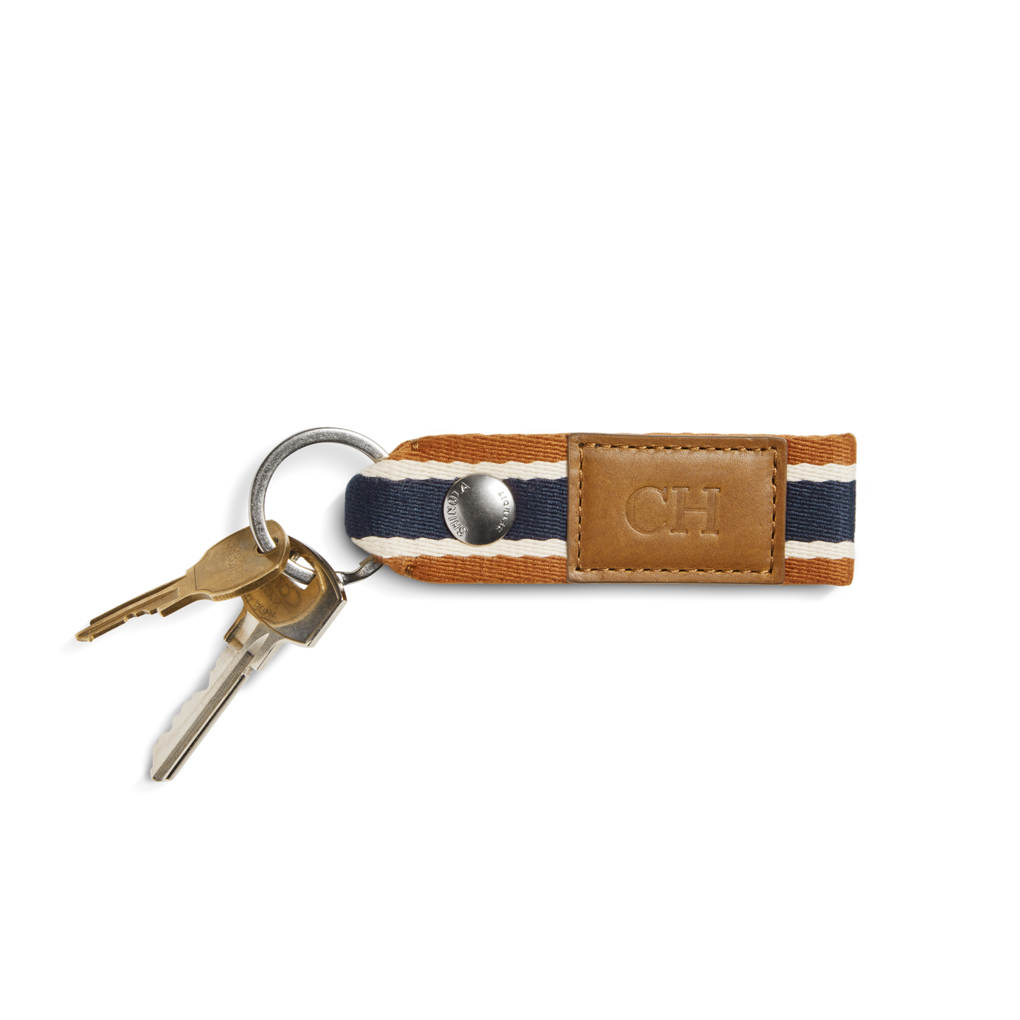 Two keys on a silver keyring are attached to the Shinola Webbing Keychain - Brand Stripe / Tan, featuring dark blue, white, and brown stripes and a tan leather patch perfect for monogramming.