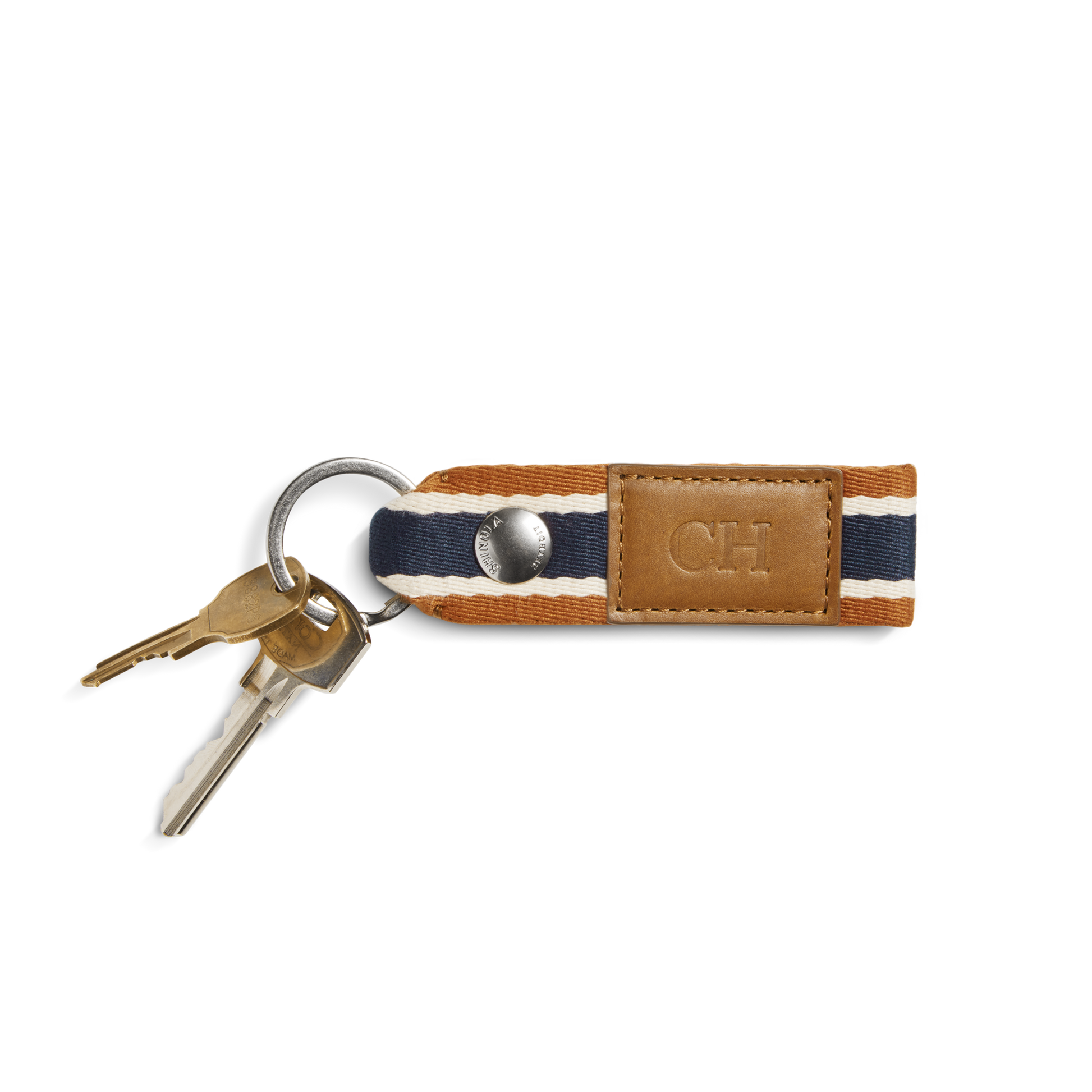 Two keys on a silver keyring are attached to the Shinola Webbing Keychain - Brand Stripe / Tan, featuring dark blue, white, and brown stripes and a tan leather patch perfect for monogramming.