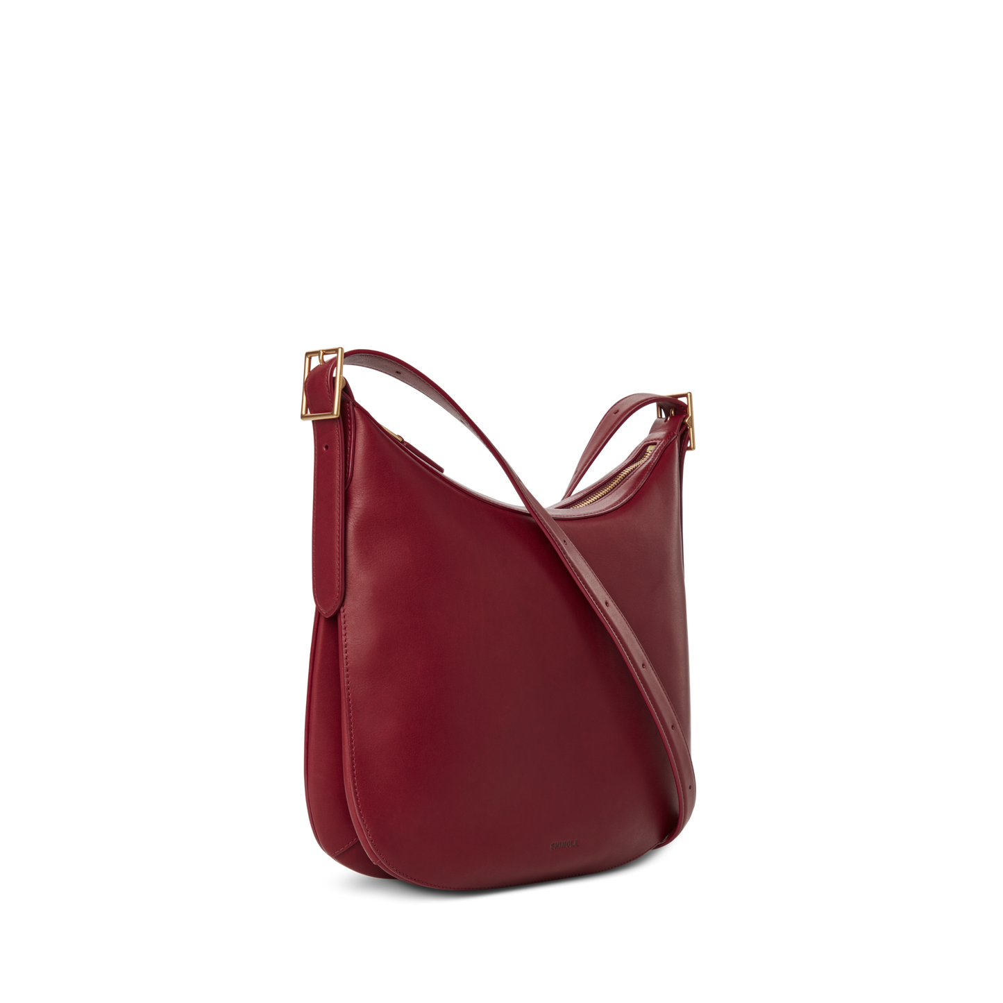 The Shinola Medium Bixby Crossbody - Ruby features a curved silhouette, adjustable strap, and gold-tone buckle accents, shown against a plain white background for an effortlessly versatile look.