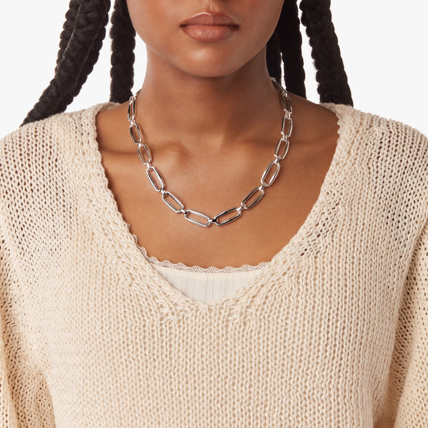 A woman models the Shinola Signature Chunky Link Necklace in sterling silver, worn over a cream knit sweater and white top. Only her lower face and upper torso are shown.