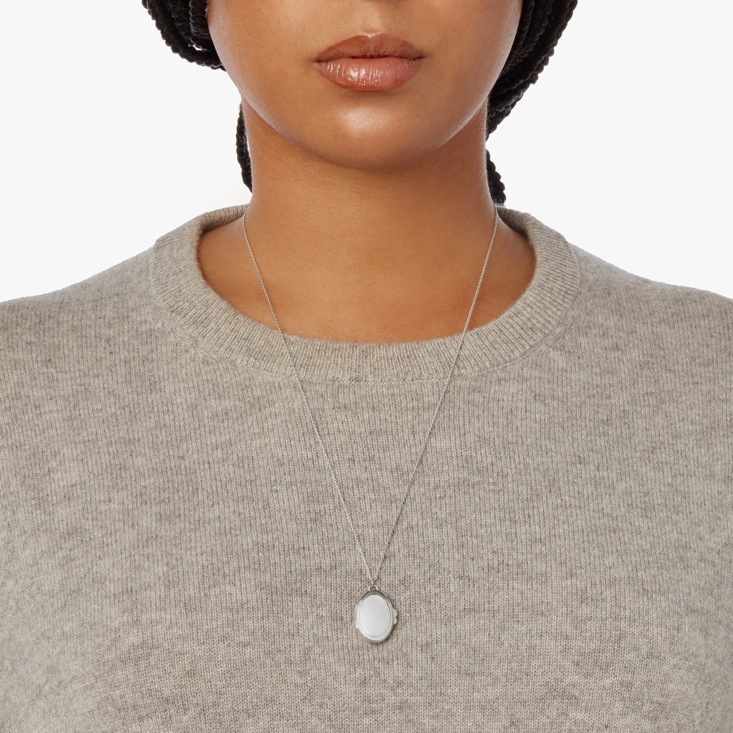 A woman wears the Shinola Heirloom Statement Locket Necklace in sterling silver and a light gray knit sweater, shown from the shoulders up against a plain white background.