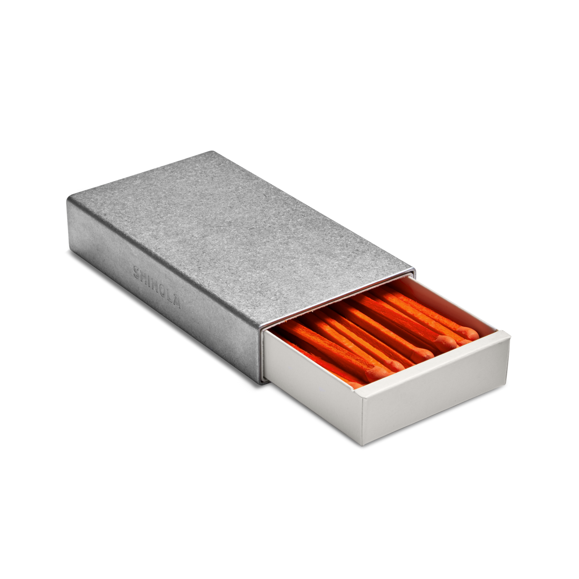 The Shinola Aluminum Matchbox Set features a rectangular, engravable case with a sliding drawer partially open to display neatly arranged orange-tipped matches inside.