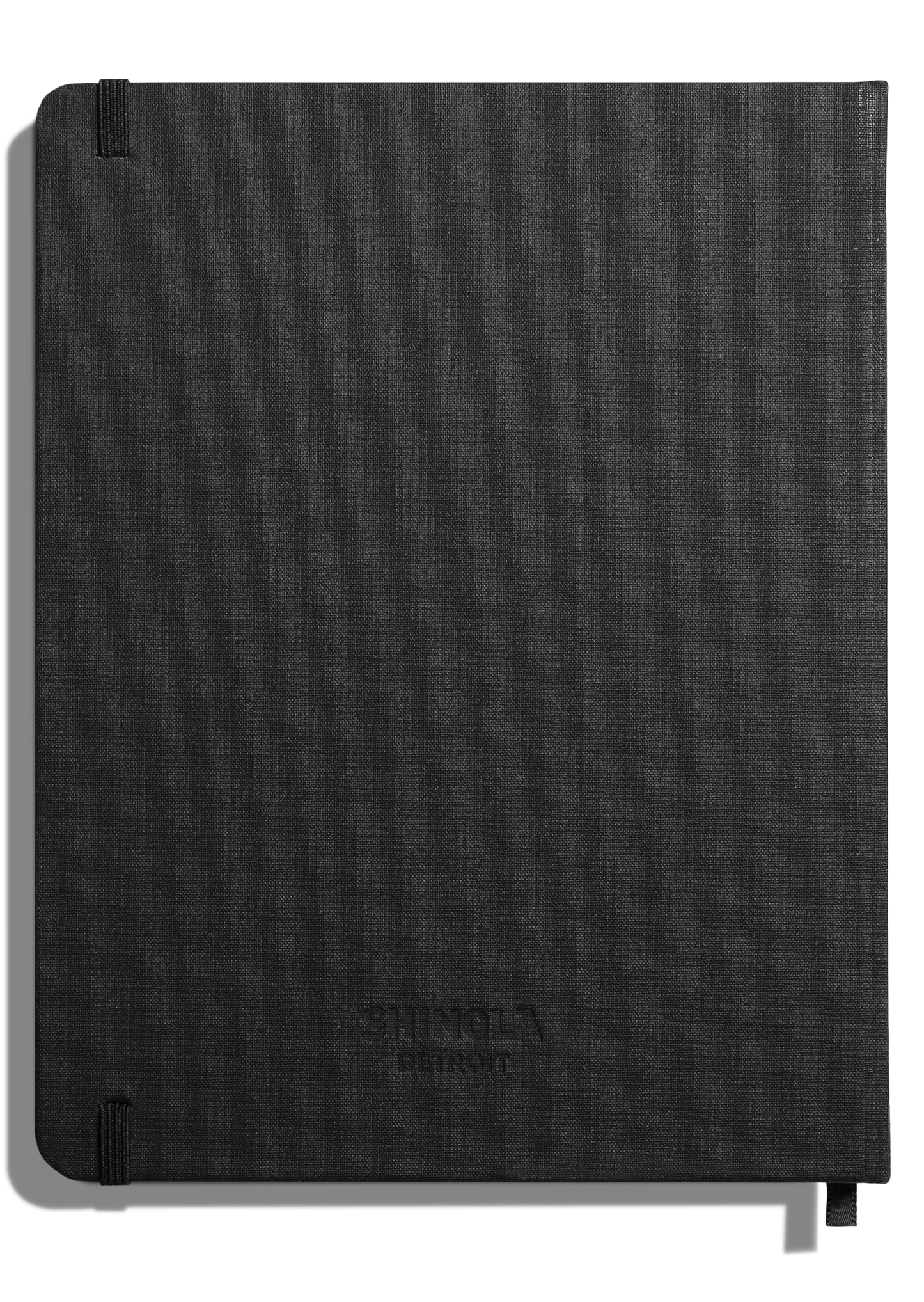 The Shinola Large Hard Plain Journal in black features a fabric-textured cover with rounded corners, an elastic band at the lower left, and a subtly embossed Shinola logo near the center.