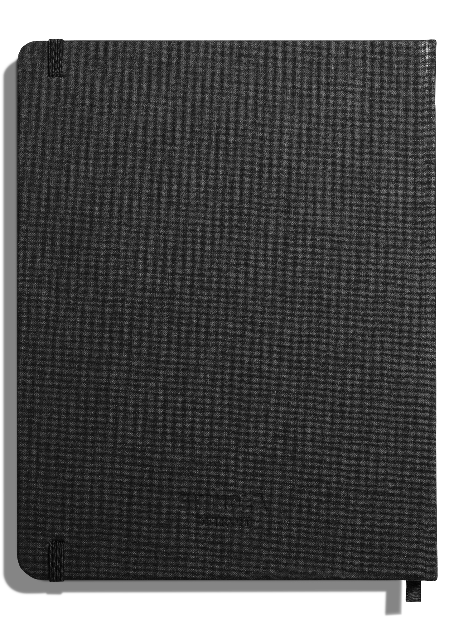 The Shinola Large Hard Plain Journal in black features a fabric-textured cover with rounded corners, an elastic band at the lower left, and a subtly embossed Shinola logo near the center.