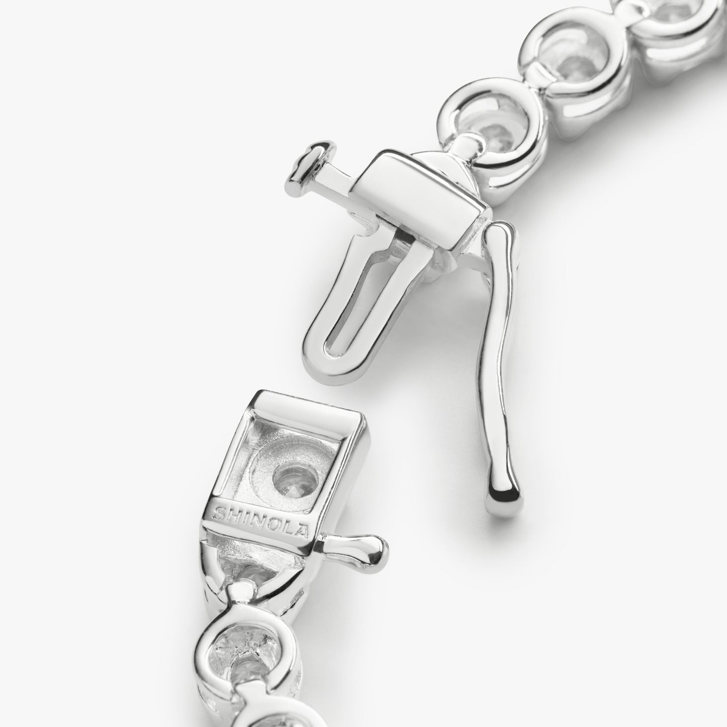 Close-up of the Shinola 3 Carat 7" Diamond Tennis Bracelet in white gold, featuring a box clasp with safety latch, open clasp mechanism, and circular links. "SILMCLA" is engraved on part of the clasp.