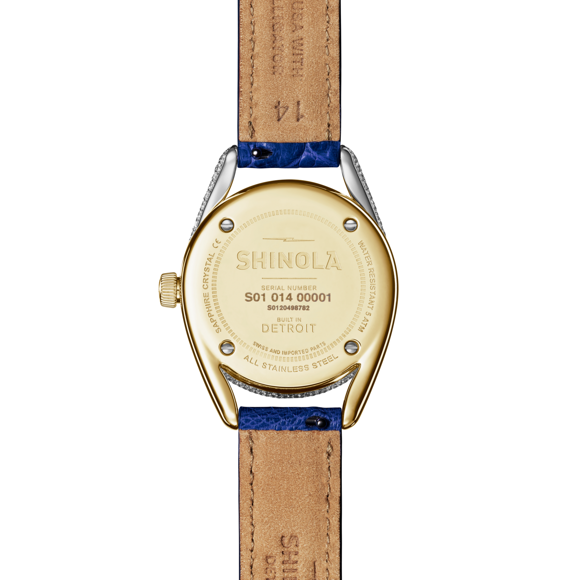 The back of a Shinola Diamond Derby Watch with a gold-toned two-tone case, engraved serial number, "Built in Detroit" text, and a blue Sapphire Alligator strap with visible stitching on the tan leather underside.