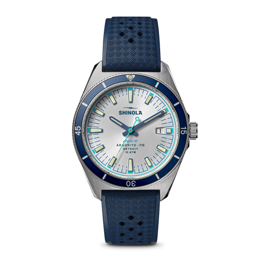 The Shinola Duck Watch - Midnight Blue features a stainless-steel case, white and blue dial, blue bezel, dark blue textured rubber strap, silver hour markers and hands, and displays 10:08.
