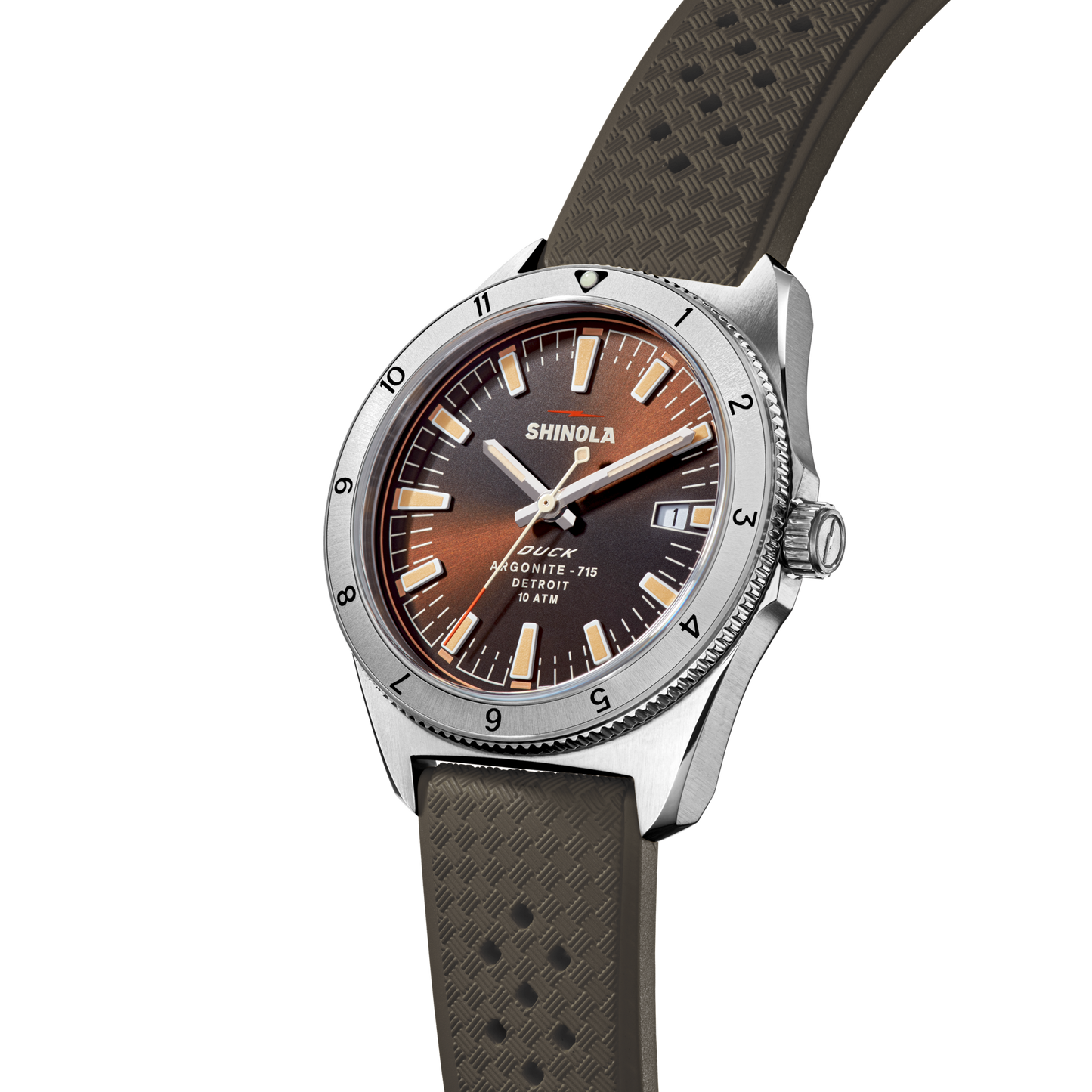 The Shinola Duck Watch - Mallard Brown features a brown gradient dial, silver bezel with black markers, a textured brown strap, and displays the time with "SHINOLA" and "Argonite-715, 100M/330FT" on the face.