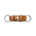 The Shinola Leather Valet Key Fob in tan features two silver rings, white stitching, and a buttoned center strap. This leather keychain is shown on a plain white background.