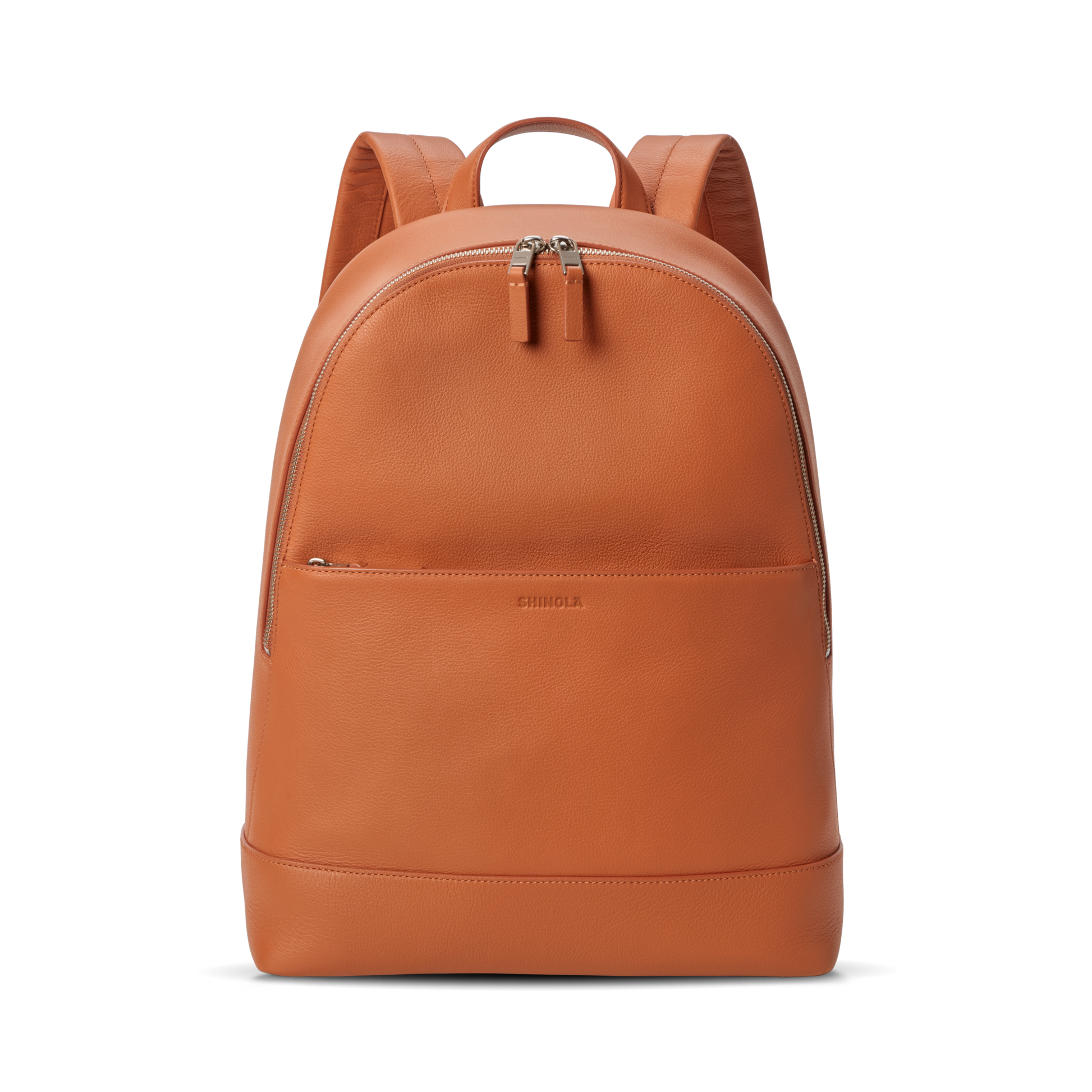 The Shinola Canfield Backpack in Rust is a sleek orange leather bag with a front zip pocket, dual zipper pulls on the main compartment, and padded shoulder straps—perfect for stylish travel—shown against a plain white background.