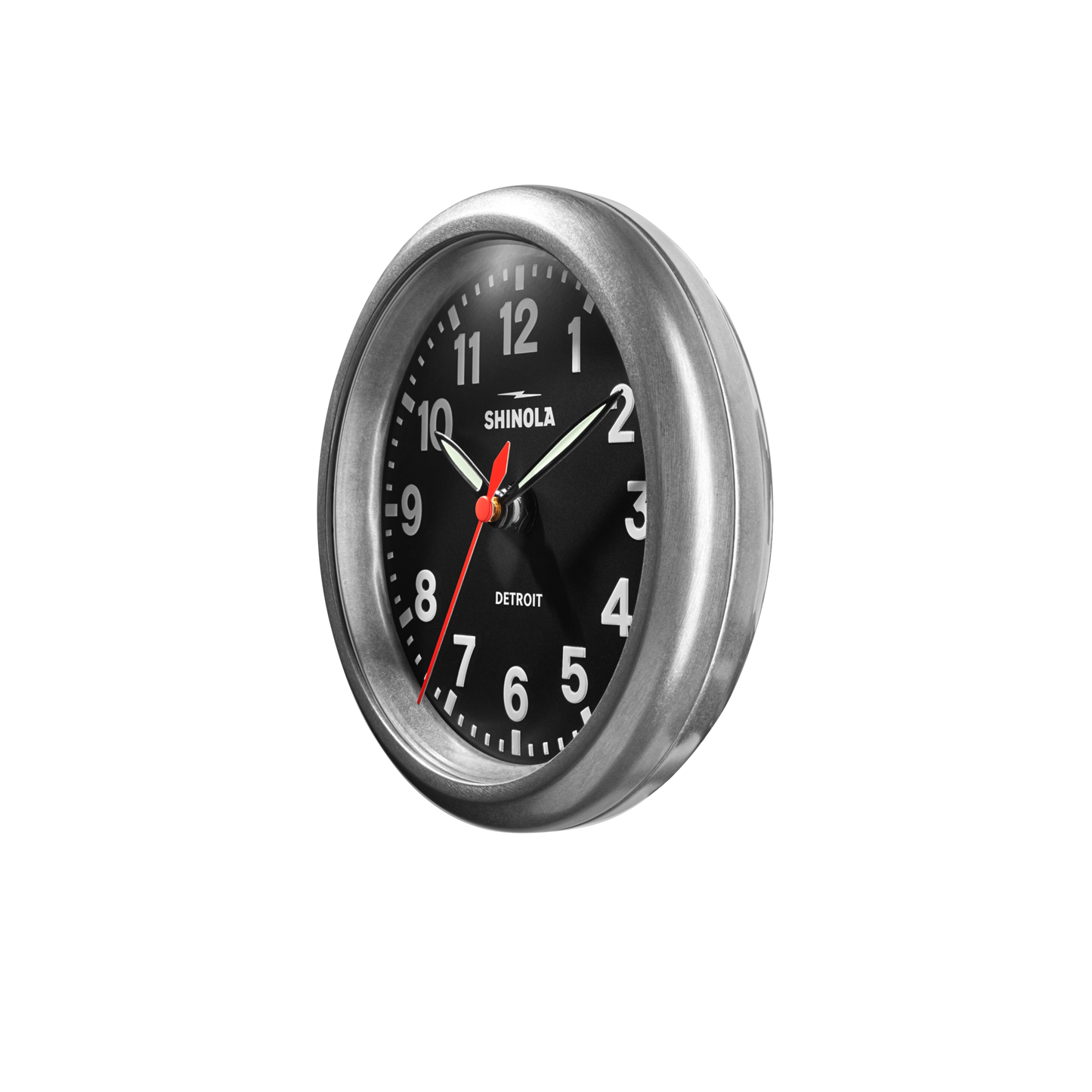 The Shinola 6" Runwell Clock in Tumbled Zinc features a round metal frame, black face, white numbers, and three hands. The time shown is around 10:10:38.
