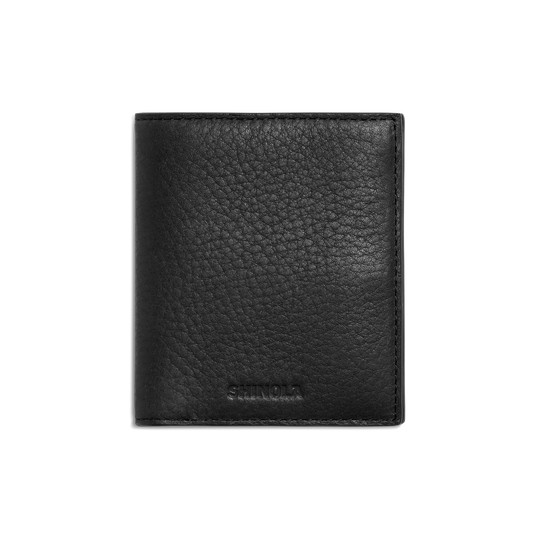 The Shinola Coin Bifold - Black is a slim wallet made from Natural Grain Leather, featuring a textured surface and the SHINOLA logo subtly embossed near the bottom on a plain white background.