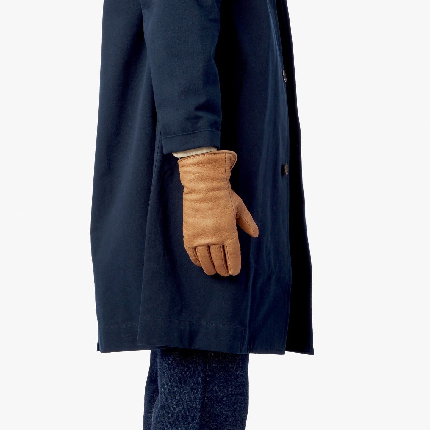 A person wears a dark blue trench coat and tan Lined Leather Gloves by Shinola.