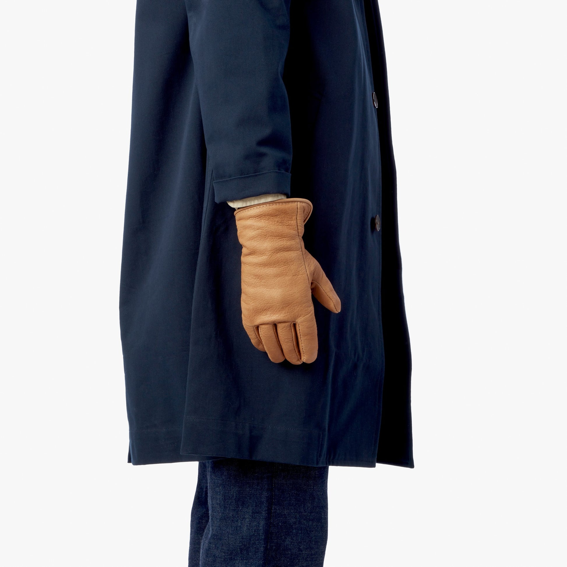 A person wears a dark blue trench coat and tan Lined Leather Gloves by Shinola.