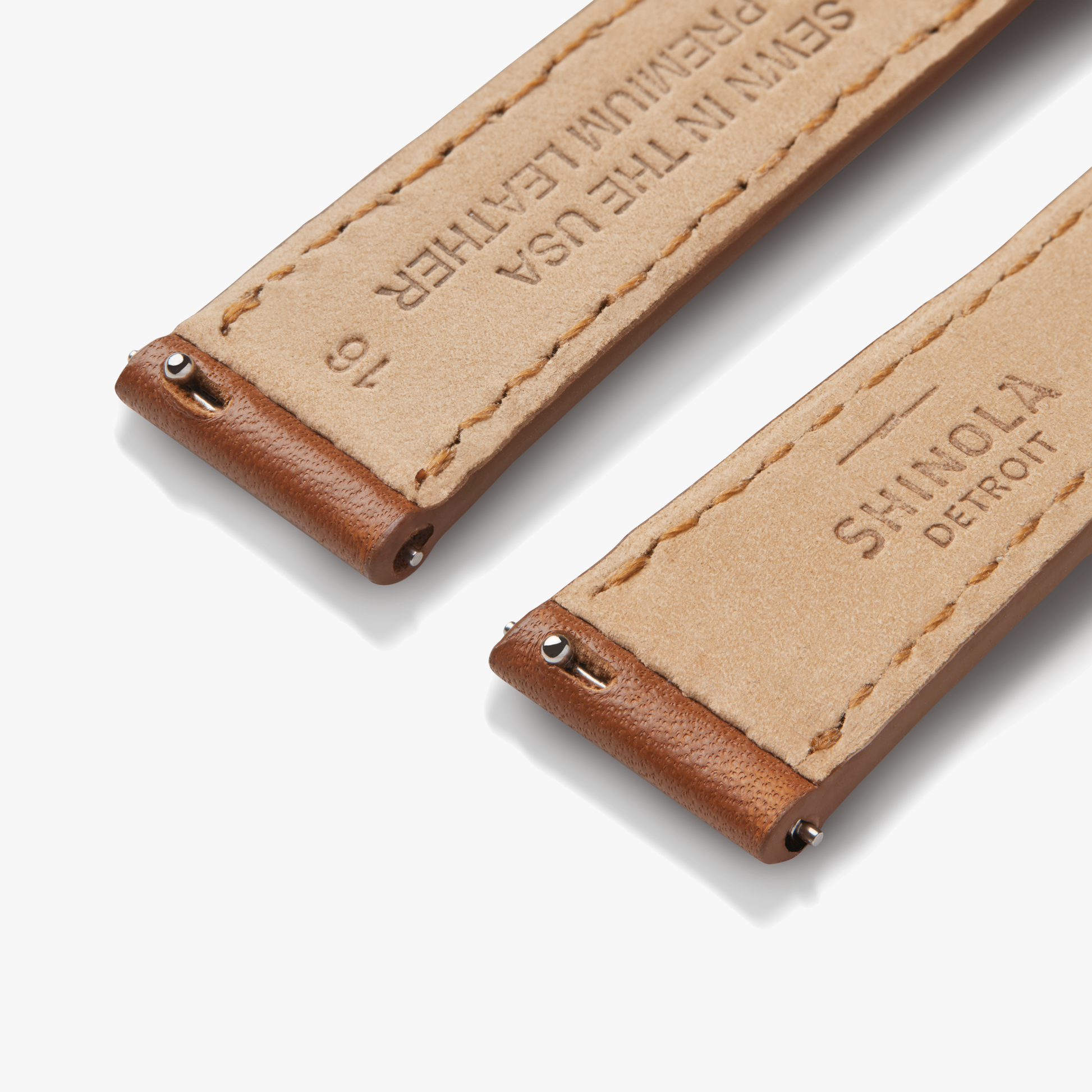Close-up of two Shinola 16mm Leather Watch Straps in tan with brown edging, silver pins, and “SHINOLA DETROIT” plus “SEWN IN THE USA PREMIUM LEATHER” stamps, designed for easy customization.