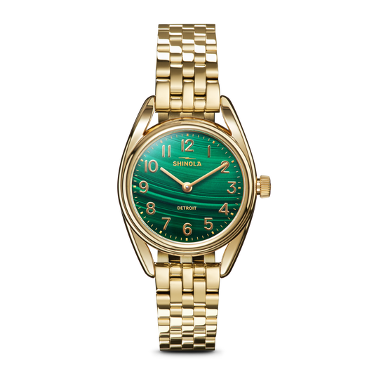 The Shinola Derby Watch - Malachite features a gold stainless steel case, malachite dial, gold hour markers and hands, and a gold link bracelet. Assembled in Detroit, the watch displays the Shinola brand on its face.