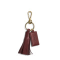 The Shinola Leather Tassel Keychain in Merlot features a brown leather fringe tassel and rectangular tag with embossed text, all attached to a gold keyring and clasp. Displayed against a plain white background.