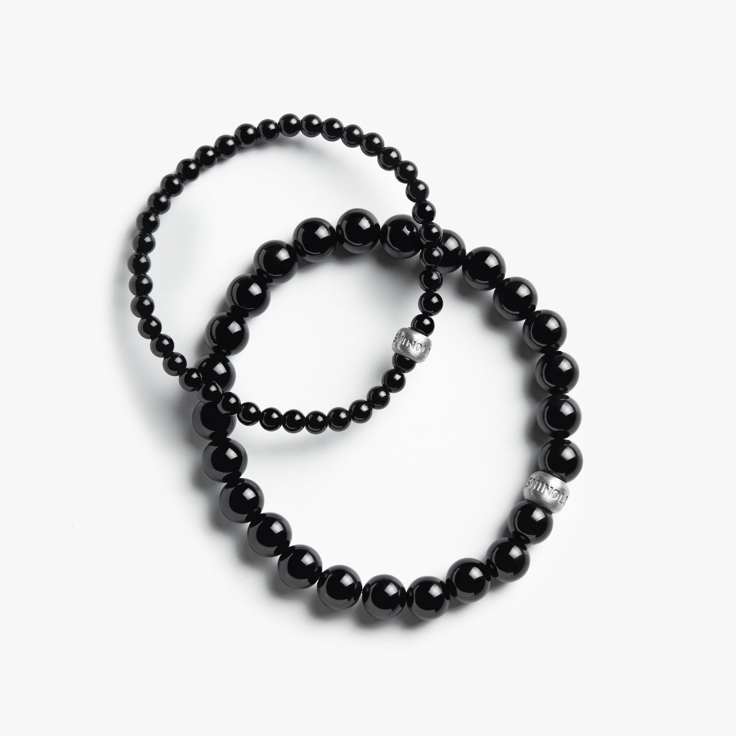 Shinola's 4mm Beaded Onyx Bracelets—two sizes, each with sterling silver accents—are styled in classic onyx fashion and elegantly arranged on a white background.