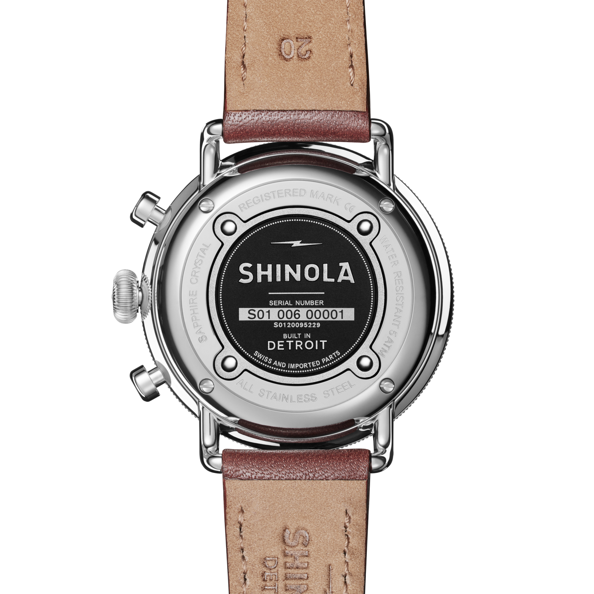 The back of a Shinola Canfield 2 Eye Chrono - Black wristwatch with a brown leather strap displays the serial number, “Built in Detroit,” and sapphire crystal details engraved around the stainless steel case.