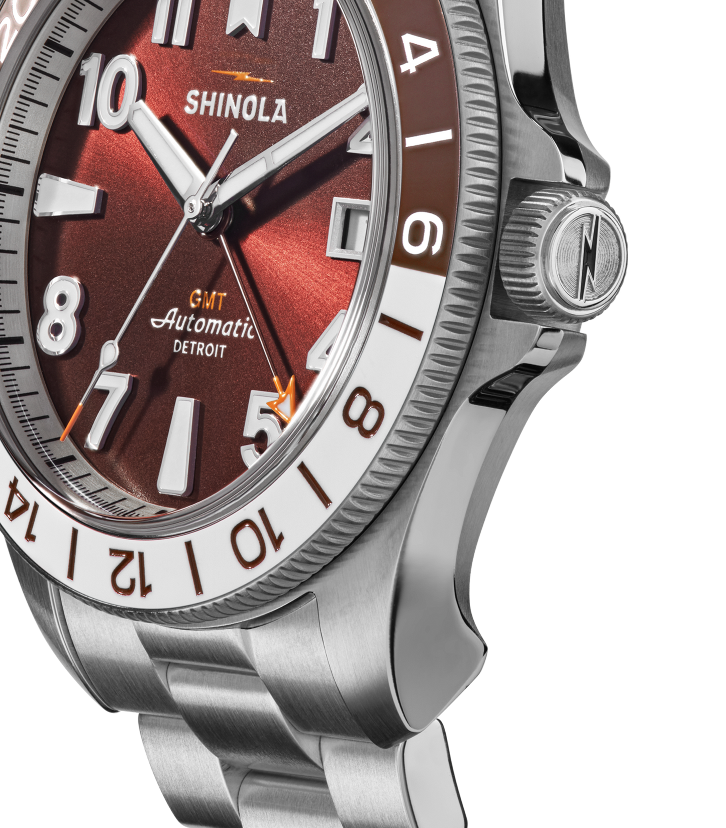 Close-up of a Shinola Monster GMT Automatic Watch - Whiskey featuring a red dial, silver hour markers, stainless steel bracelet, and a bezel with brown and white numerals to highlight its automatic movement.