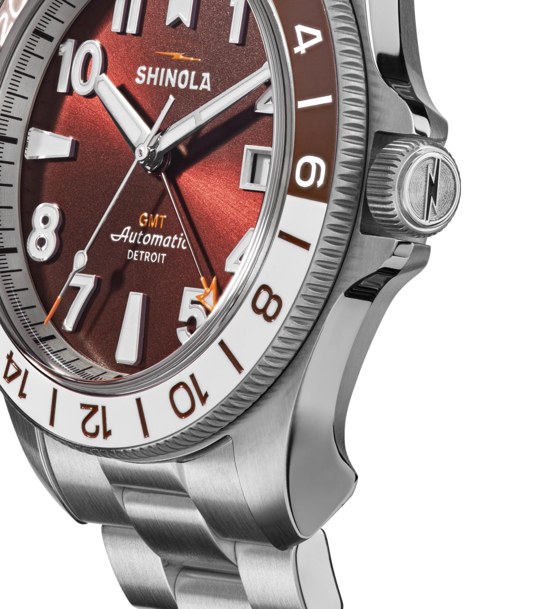 Close-up of a Shinola Monster GMT Automatic Watch - Whiskey featuring a red dial, silver hour markers, stainless steel bracelet, and a bezel with brown and white numerals to highlight its automatic movement.