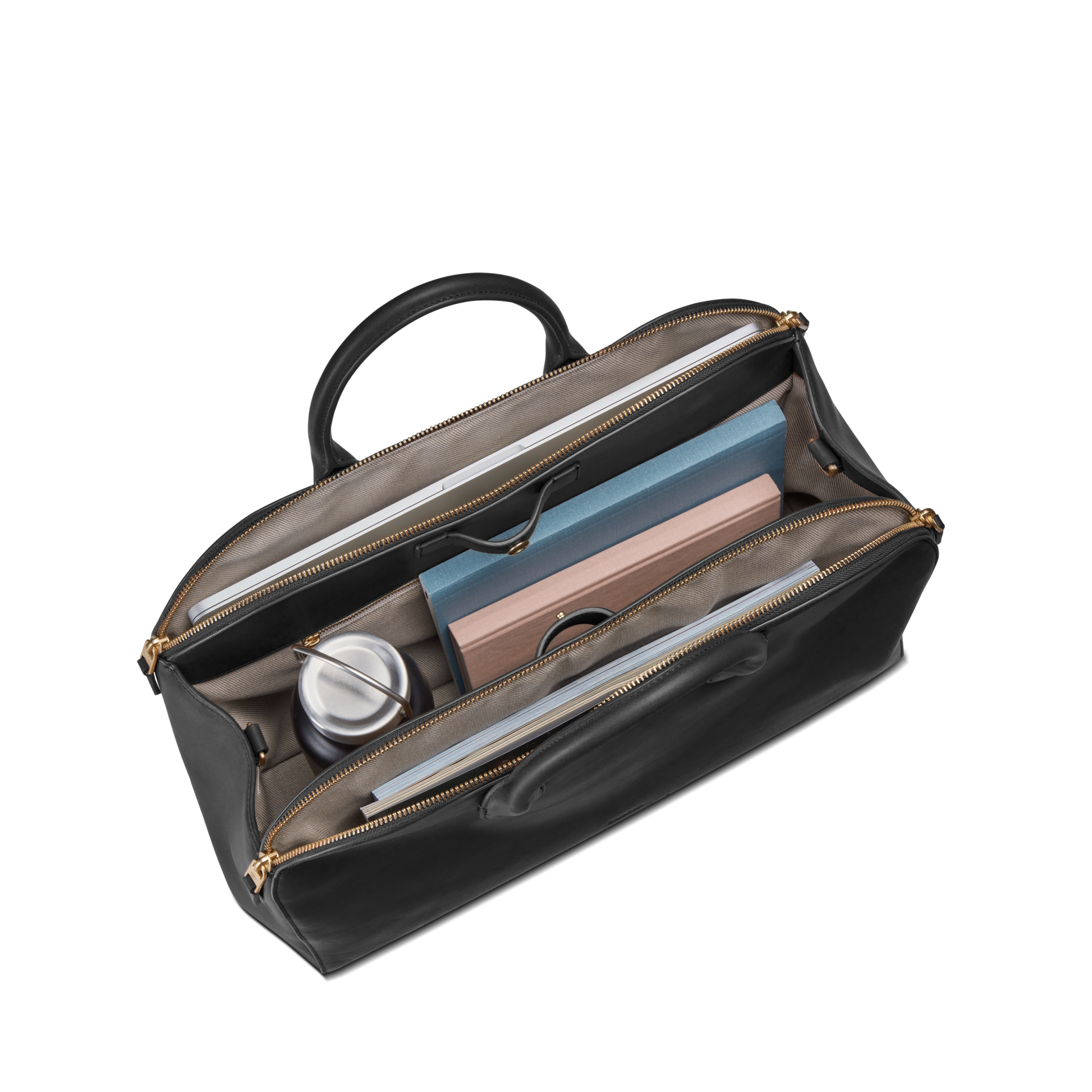 The Shinola Bixby Work Satchel - Black in natural leather with open zippers displays organized compartments holding a reusable cup, a pink and blue notebook, and a rolled-up magazine.