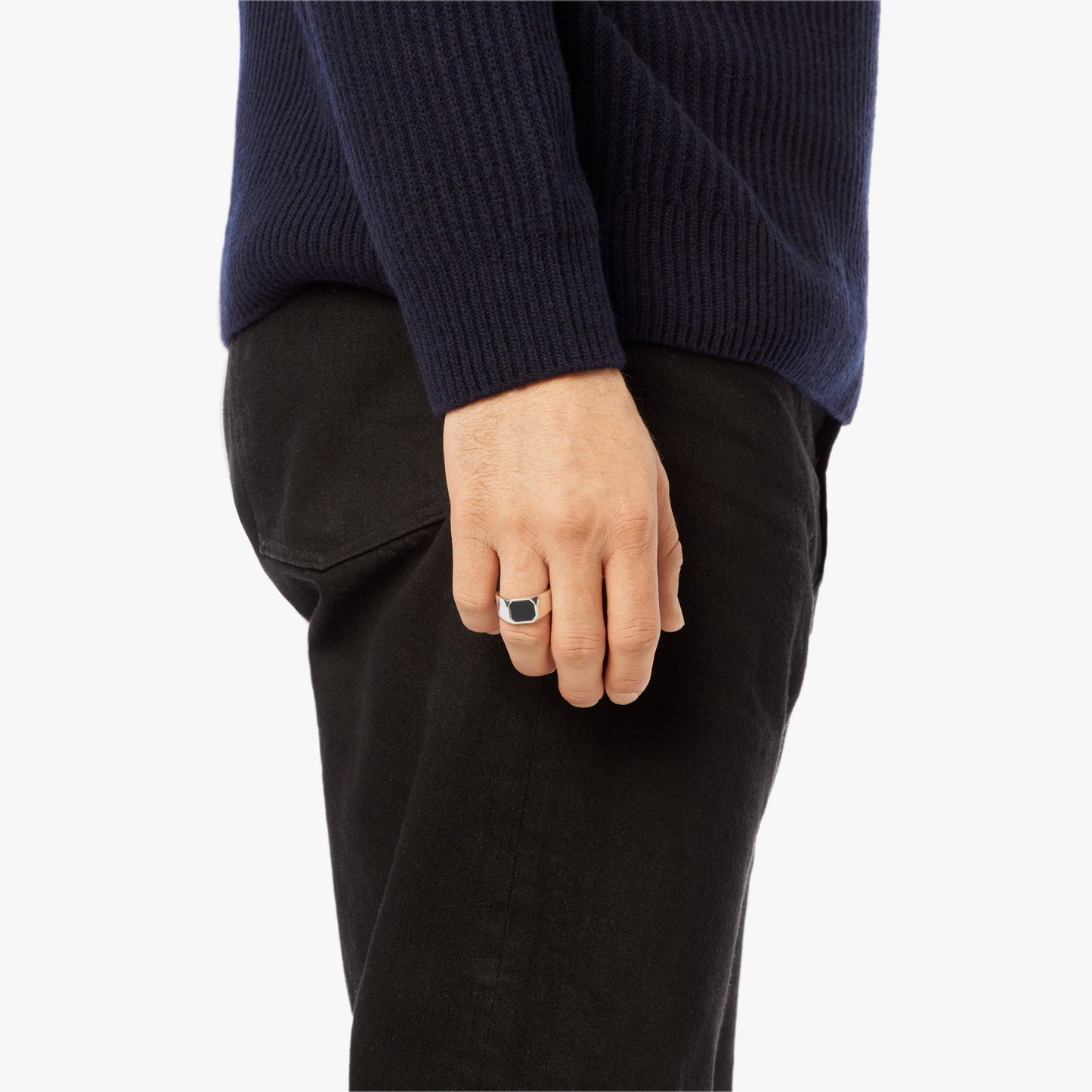 A person in a navy sweater and black pants is shown from the side, their hand by their hip displaying the Shinola Octagonal Onyx Signet Ring in sterling silver on their finger.
