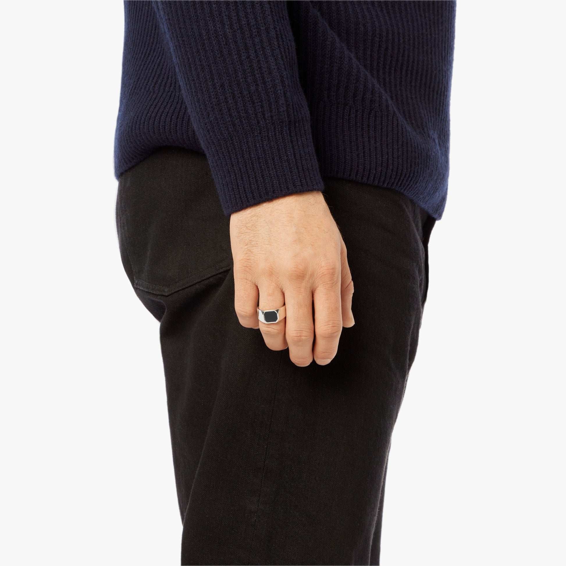 A person in a navy sweater and black pants is shown from the side, their hand by their hip displaying the Shinola Octagonal Onyx Signet Ring in sterling silver on their finger.