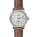 The Shinola Runwell Watch - Ivory features a round silver case, ivory dial with Arabic numerals, date window at 3 o’clock, and a brown leather strap. The watch face displays the time as 10:08:36.