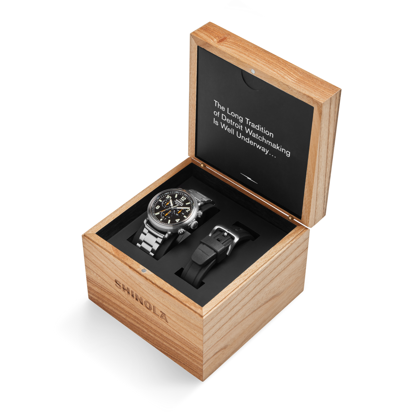 A Shinola Runwell Chronograph West Wind Watch Gift Set with an additional black strap is displayed in a wooden box with its lid open, revealing the text: "The Long Tradition of Detroit Watchmaking Is Well Underway…".