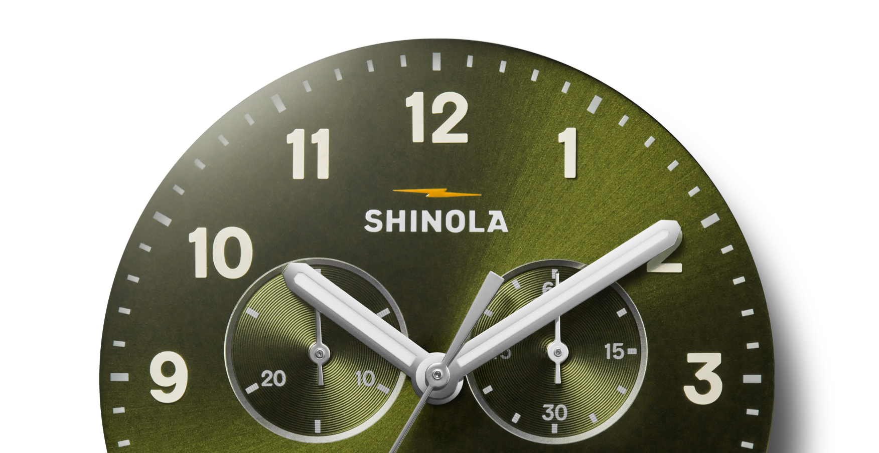 Close-up of the Shinola Canfield Chronograph Watch - Dark Olive, featuring a green dial with white hour markers, two subdials, three silver hands at 10:09:39, and the Shinola logo below 12 o'clock.