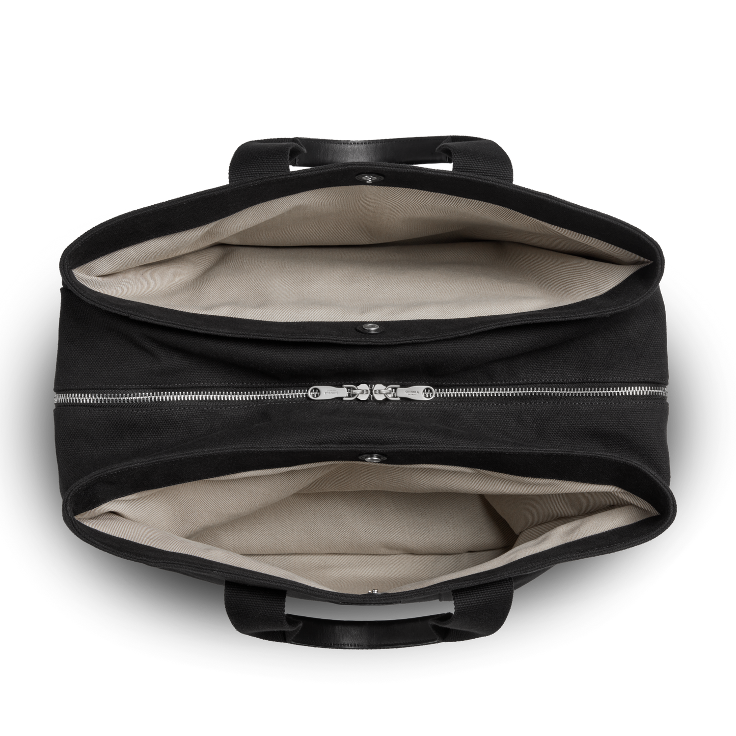 A top view of the Shinola Runwell Canvas Duffle Bag in black shows two roomy compartments with a central zippered divider, light beige lining, and black handles—perfectly sized for use as a TSA-approved travel carry-on.