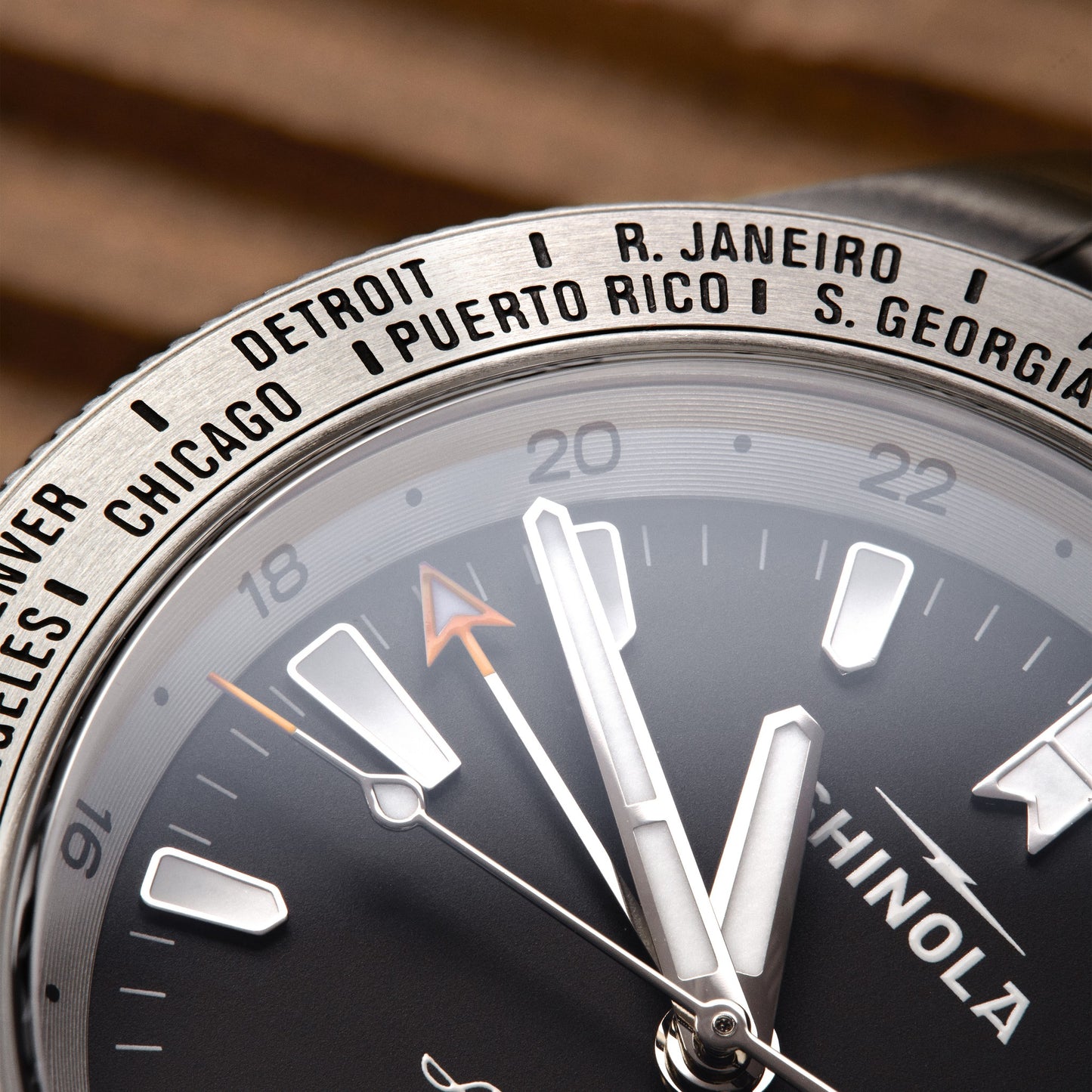 Close-up of the Shinola Monster Worldtimer GMT Watch, featuring hour, minute, and second hands plus a reflective bezel listing cities like Detroit, Chicago, and R. Janeiro—perfect for globetrotters.