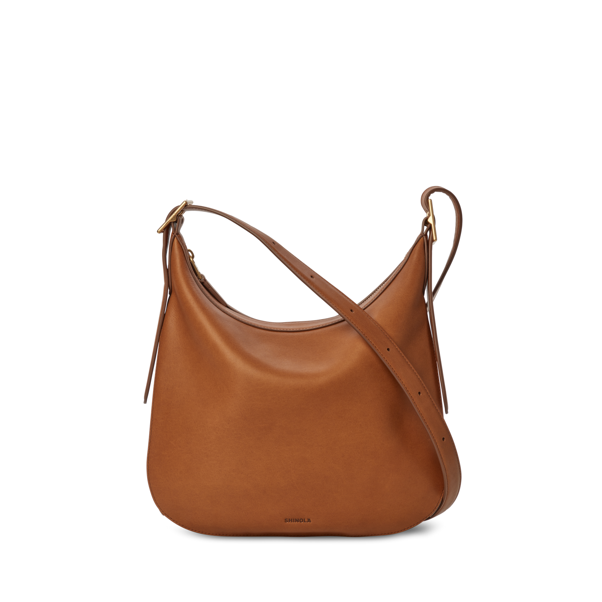 The Shinola Medium Bixby Crossbody - Tan features brown natural leather, a curved top, adjustable strap, and minimal design—versatile and perfectly displayed against a plain white background.