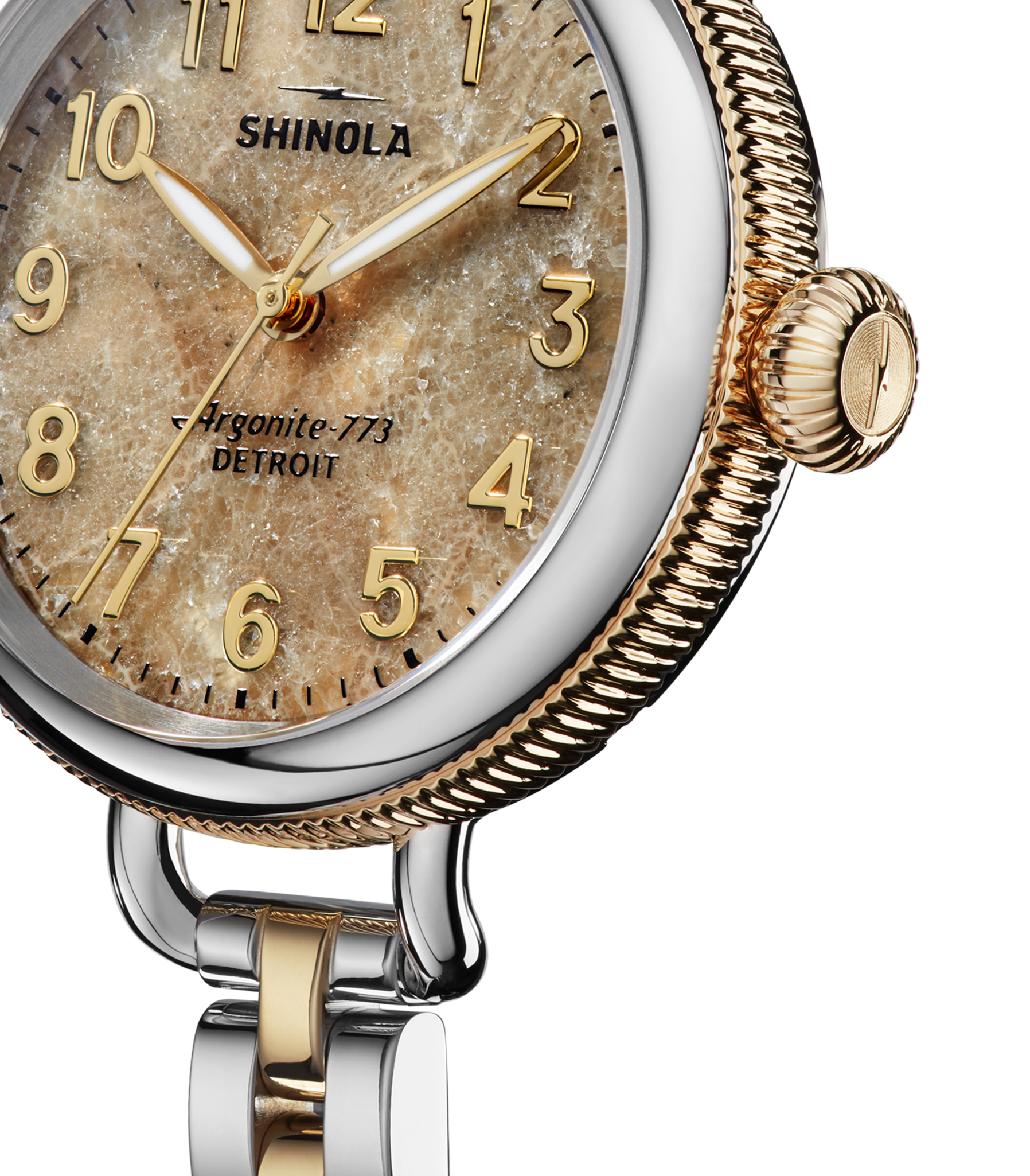 Close-up of the Shinola Birdy Watch - Petoskey, featuring a textured sandy dial, gold-toned numbers and hands, a two-tone gold and stainless steel case and matching band. "Shinola" and "Detroit" are visible on the face.