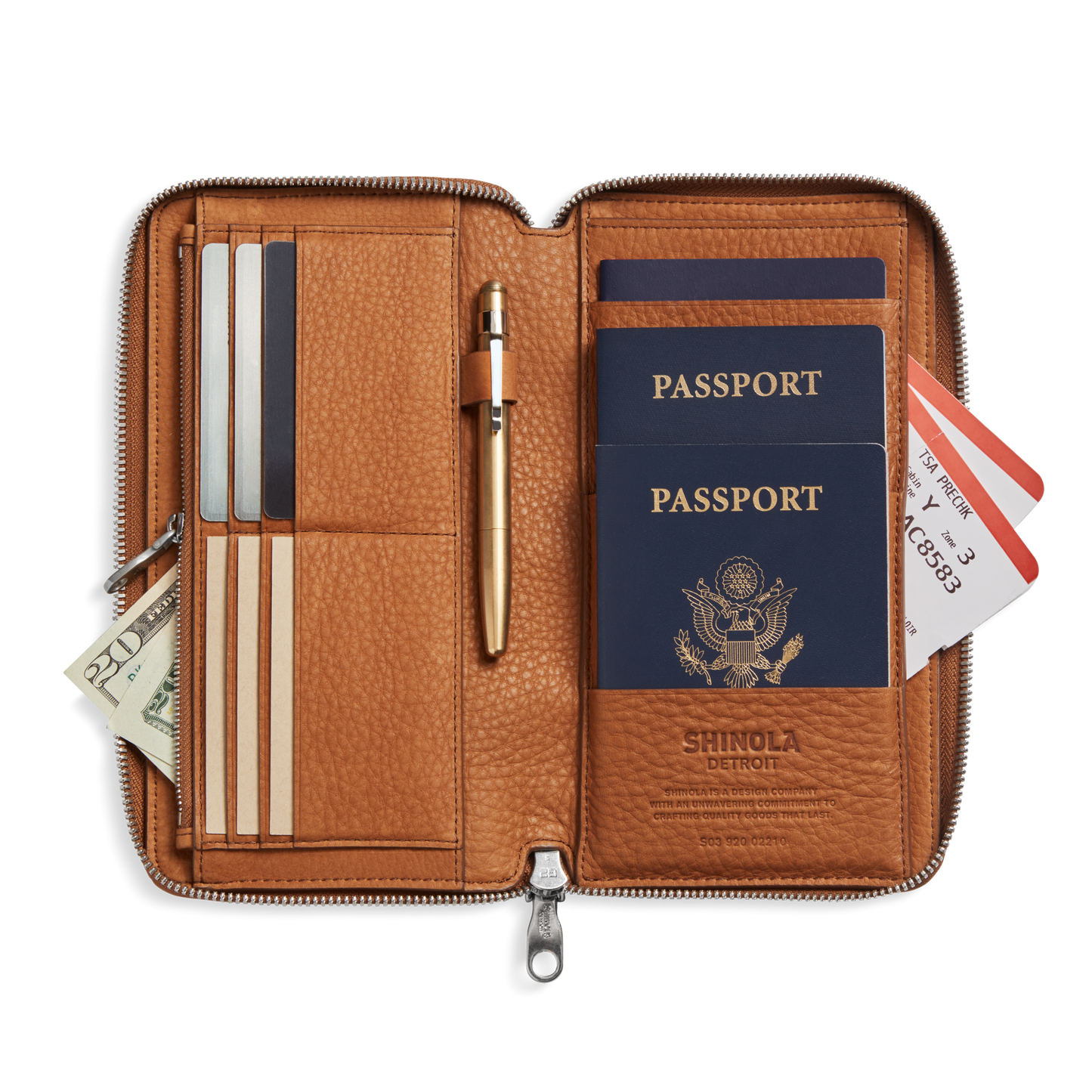The Shinola Organizer Wallet - Tan is open, displaying two U.S. passports, a pen, cards, cash, credit cards, and boarding passes neatly organized inside this travel wallet.